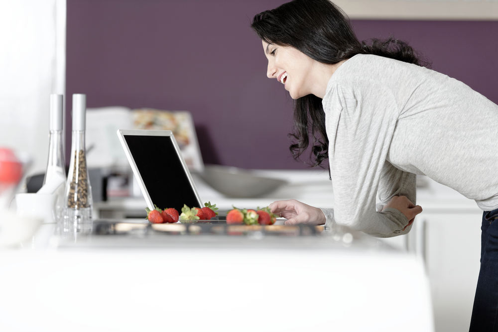 Young woman reading recipe from her laptop